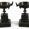 A pair of 19th Century bronze twin handled urns, on square black marble bases, 20cm high.