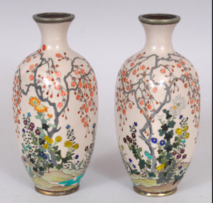AN UNUSUAL MIRROR PAIR OF JAPANESE MEIJI PERIOD SILVER WIRE CLOISONNE & GIN BARI BEIGE GROUND CLOISONNE VASES, each decorated in fine detail with a continuous riverbank scene of flowers and overhanging blossoms, 5.1in high.
