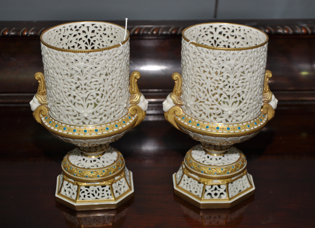 Pair of Grainger & Co. pot pourri vases, each of urn form with bodies, bases and plinths pierced with tracery, female head form handles and gilt detailing with blue enamel jewelled studding, height 21cm, printed factory mark to bases, inscribed "1694" Pair of Grainger & Co. pot pourri vases, each of urn form with bodies, bases and plinths pierced with tracery, female head form handles and gilt detailing with blue enamel jewelled studding, height 21cm, printed factory mark to bases, inscribed "1694"
