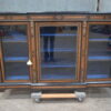 A Victorian amboyna and inlaid ebonised three-door breakfront bookcase. With gilt mounts Fixed shelves. With key.