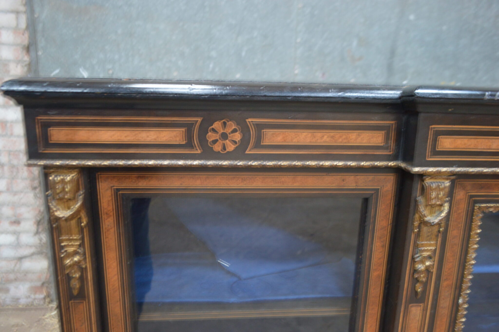 A Victorian amboyna and inlaid ebonised three-door breakfront bookcase.