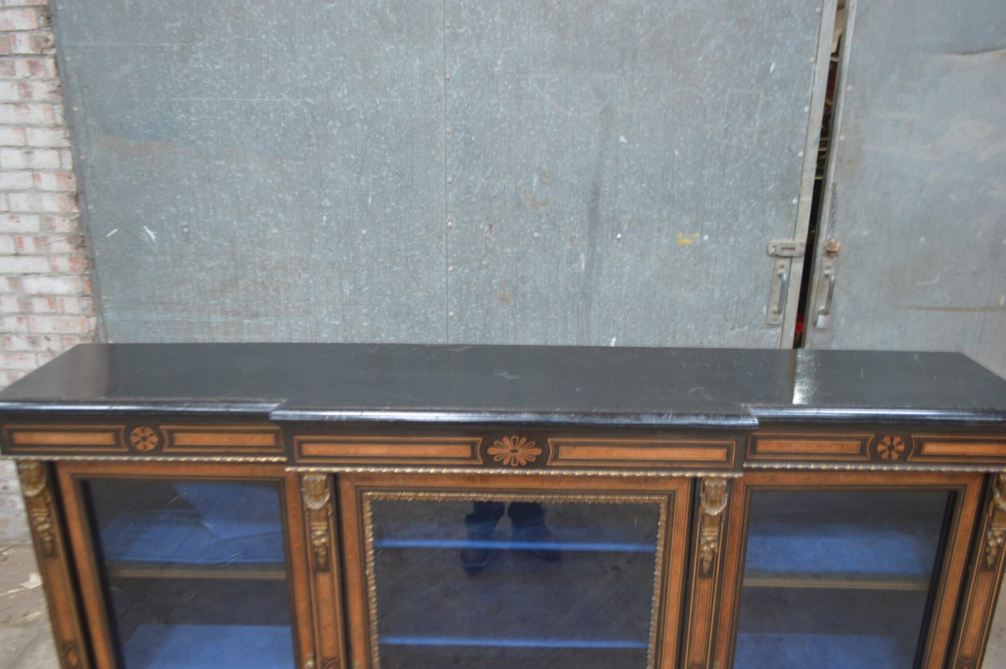 A Victorian amboyna and inlaid ebonised three-door breakfront bookcase.