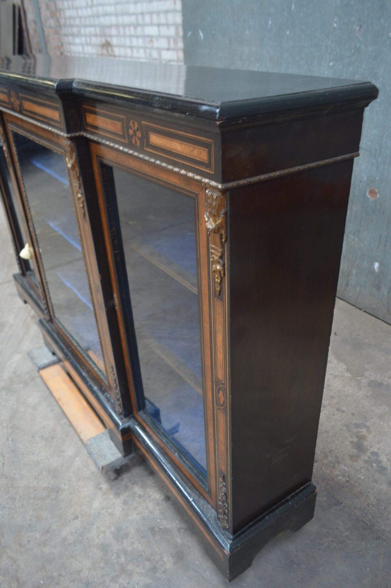 A Victorian amboyna and inlaid ebonised three-door breakfront bookcase.